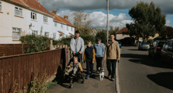 Family walking in a village through affordable housing by Abigail Oliver