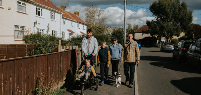 Family walking in a village through affordable housing by Abigail Oliver